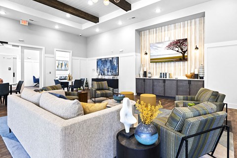 A living room with a grey couch and a blue vase on a black table.